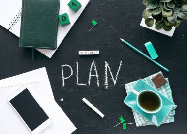Geleceği planlamak. Masaüstü grafit stoğunun üst görüntüsü. Masanın üzerinde bir defter, bir fincan çay, kantin, yıllar, telefon, takvim var..