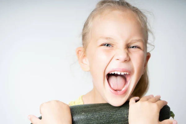 Little girl holds with zucchini on a white background — Stock Photo, Image