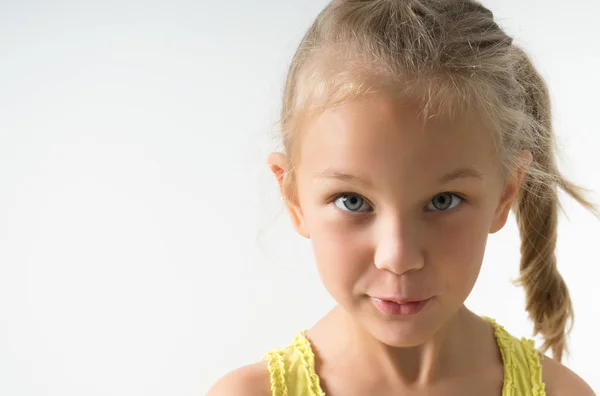 Little blonde girl of 5 years old looks inquiringly in surprise at the frame, closeup isolated on a light background — Stock Photo, Image