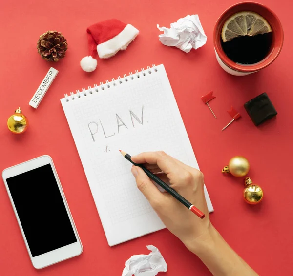 Werkruimte op kerstavond en nieuwjaar, voorbereiding op de vakantie- en cadeaulijst. met blanco klembord, toetsenbord, briefpapier, potlood en theekopje op een rode achtergrond. — Stockfoto