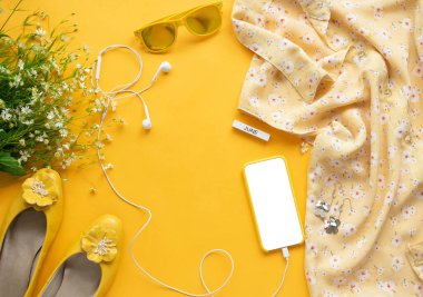 Kız yaşam tarzı aksesuarlarının fotoğrafını çek. Modern bir kadının rastgele nesnelerinin olduğu bir hayat. Çiçekli bluz, kulaklık, telefon, küpe, güneş gözlüğü, ayakkabı, üst manzara..