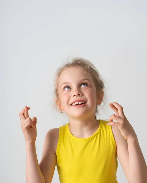 Nice girl preschooler hopefully looking up holding fingers crossed for good luck. Cropped studio portrait isolated on white, copy space — Stock Photo, Image