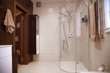 Parlak yeni banyo içi, banyo çevresinde cam yürüyüş, kahverengi makyaj dolabı ve mozaik fayansla eşleştirilmiş. .