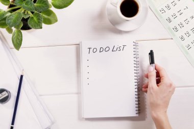 Not defterine yazılmış liste için. Tahta masada bir fincan kahveyle yapılacaklar listesi olan defter.