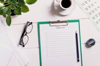 Kontrol listesi için maket, kahverengi ahşap zemin üzerinde kalem ve kahve bardağı olan boş not kağıdı. Ofis, yazar veya öğrenim kavramı