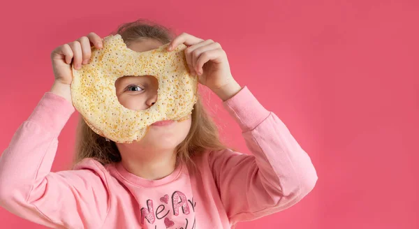 Küçük tatlı kız bir krep tutuyor ve pembe arka planda bir delikten bakıyor. Güzel kahvaltı. bahar festivali karnavalı