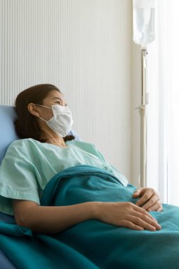 Maske takan ve grip ve zatürreeden hastalanan Asyalı kadın hasta. Hastanenin koğuşuna yatırıldı. Sağlık ve Tıp Konsepti