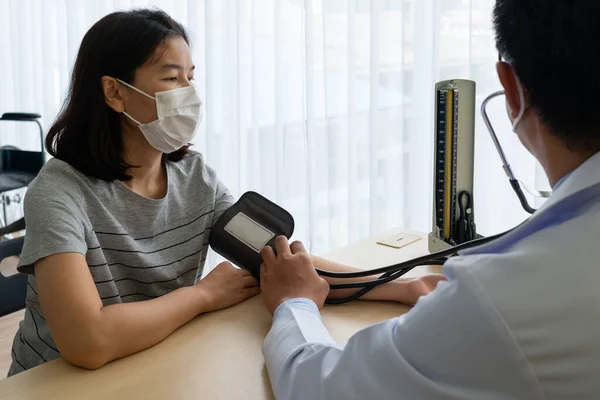 高血圧の女性患者の血圧を測定し 病院の診療所で彼を訪問するためにSphygmomanometerを使用してアジアの医師 医療と医療の概念 — ストック写真