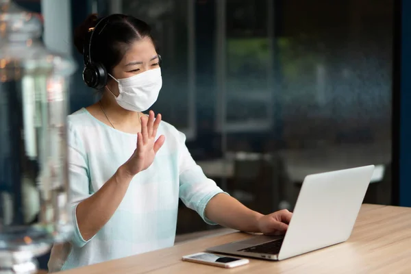 Young Asian Woman Wearing Face Mask Headphones Working Remotely Using — Stock Photo, Image