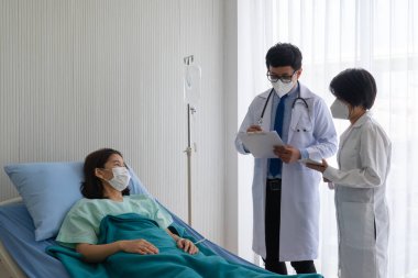 Hastanedeki hasta hastaları tedavi etmek için maske takan Asyalı doktor öğretiyor. Sağlık ve Tıp Fakültesi kavramı