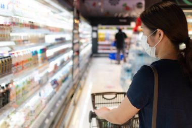 Maske takan genç Asyalı kadın süpermarkette alışveriş yaparken sosyal mesafeyi koruyor. yeni normal, covid-10 ve coronavirus konsepti