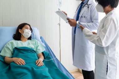 Hastanedeki hasta hastaları tedavi etmek için maske takan Asyalı doktor öğretiyor. Sağlık ve Tıp Fakültesi kavramı