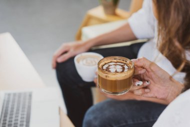 Asyalı kadın ve erkek kafede oturuyor ve sabahları ekspresso içmenin tadını çıkarıyorlar. Kafe konsepti