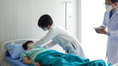 Asyalı doktor ekibi kalp krizinden bayılan yaşlı bir hastanın durumunu kontrol ediyor. Sağlık ve Tıp Konsepti