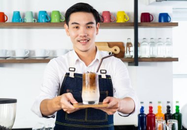 Genç adam kafede müşteriye servis yapmak için buzlu latte kahve hazırla. Kahve ve kahve dükkanı konsepti.