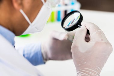 Biyoteknoloji laboratuarında yeni ilaç ve deri bakımı yapmak için eldiven giyen Asyalı bilim adamı bitki üzerinde deney yapıyor. Bilim ve gelişim kavramı
