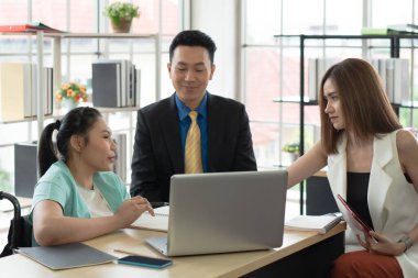 Tekerlekli sandalyede oturan ve bilgisayarla iş arkadaşlarıyla proje tartışan Asyalı engelli genç bir kadın. engelli ve engelli kavramı