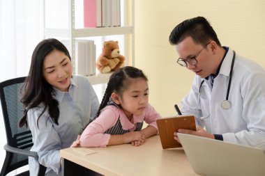 Asyalı doktor, hastanedeki pediatri kliniğini ziyaret eden genç bir kız ve anneyle konuşuyor. sağlık ve tıbbi konsept