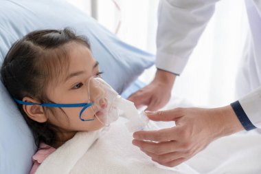 Doktor, hasta olan ve pediatri koğuşunda zatürree olan Asyalı genç kıza oksijen tedavisi uygulayın. Sağlık ve Tıp Konsepti