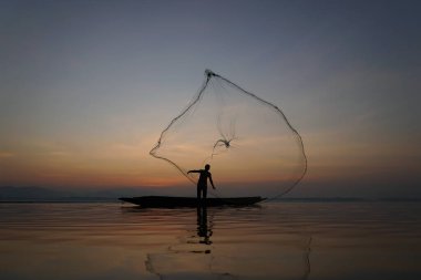 Balıkçı, sabah gölde balık avlamak için balık ağı atıyor.