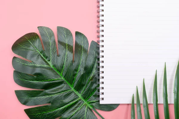 空の白い日記本ピンクの背景に植物の葉で飾られたコピースペースを持っているもの — ストック写真