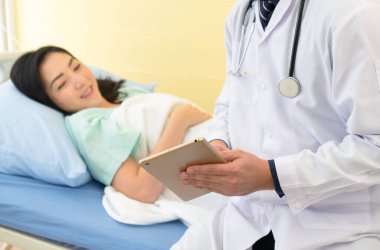 Doktor, Asyalı kadın hastayı ziyaret ediyor. Hasta ve tıp koğuşunda yatıyor. Sağlık ve Tıp Konsepti