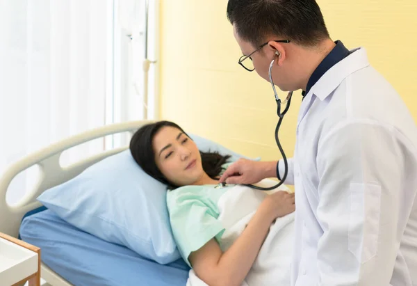 의사는 청진기를 사용하여 병상에 아시아인 여인의 소리를 듣는다 건강과 — 스톡 사진