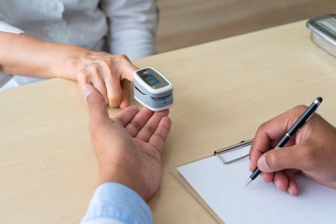 Doktor, yaşlı Asyalı kadının nabız ölçer makinesiyle oksijen doygunluğunu ölçüyor ve hastane kliniğinde normal değerde olduğunu gösteriyor. Sağlık ve Tıp Konsepti