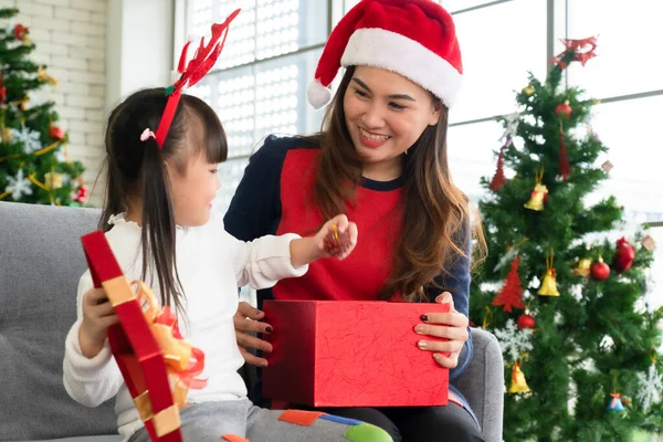 mother gives presents to her young daughter in christmas holliday. family together and relationship concept