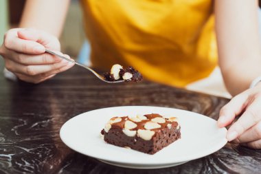 Kafede browni yemek için çatal kullanan bir kadın.