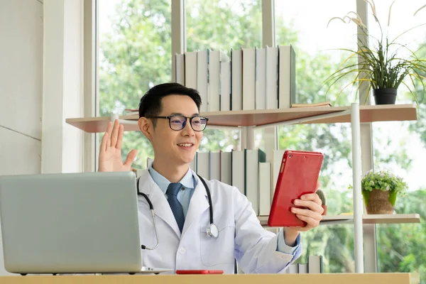 Fiatal Ázsiai Orvos Tablettával Konzultál Beteggel Videohíváson Keresztül Kórházi Irodában — Stock Fotó