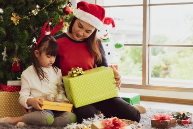 Evdeki oturma odasında, Asyalı anne genç kızına Noel hediyesi veriyor. aile ve ilişki
