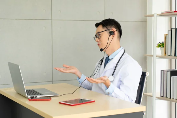 Fiatal Ázsiai Orvos Fülhallgatót Visel Számítógépet Használ Hogy Kórházi Irodában — Stock Fotó