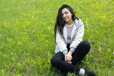 Yeşil manzarada oturan mutlu kadın.