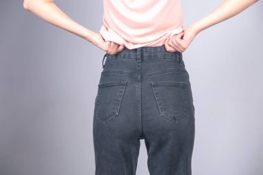 Gri arka planda kot pantolonlu seksi kadın