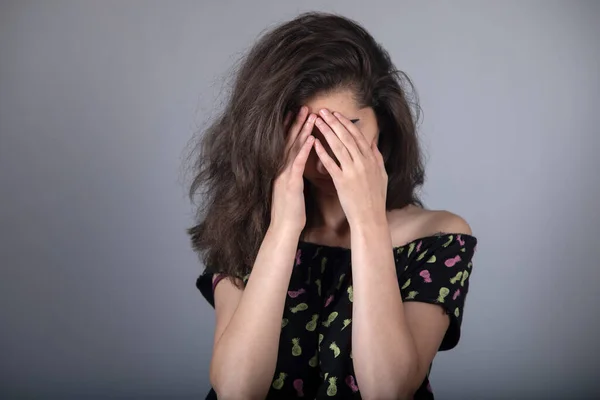 sad woman hand in face on grey background