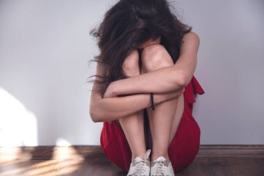 Üzgün genç kadın yerde oturuyor.