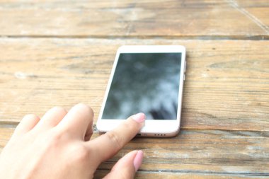 Kadın cep telefonu ahşap masada.