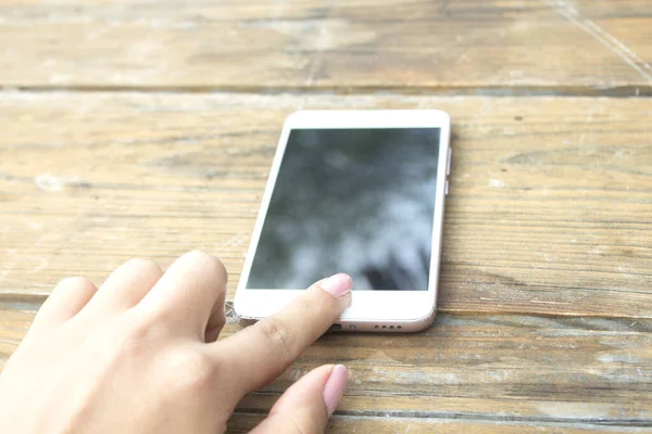 Kadın cep telefonu ahşap masada.