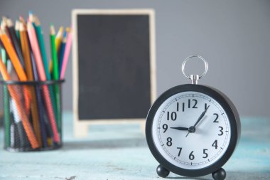 Masada kalemler olan saat ve karatahta.