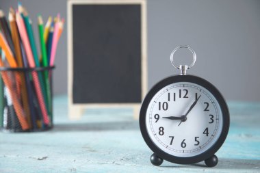 Masada kalemler olan saat ve karatahta.