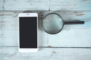 Telefon ve büyüteç masanın üstünde.