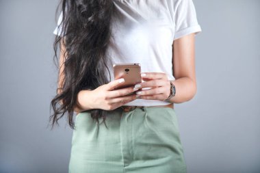 Gri sırtüstü uzanan cep telefonlarını tutan eller