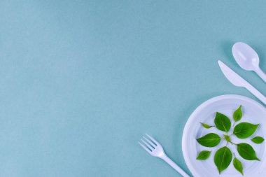 Kağıt veya plastik konsept. Sıfır atık. Mavi arka plan aletleri ve beyaz plastikten yapılmış çatal bıçaklar üzerinde tek kullanımlık. Kirlilik kavramı. Sağlıklı yiyecekler. Uzayı kopyala Minimalizm. Düz yatıyordu.