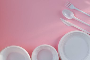Sağda ve altta pembe arka planda plastik beyaz tabaklar