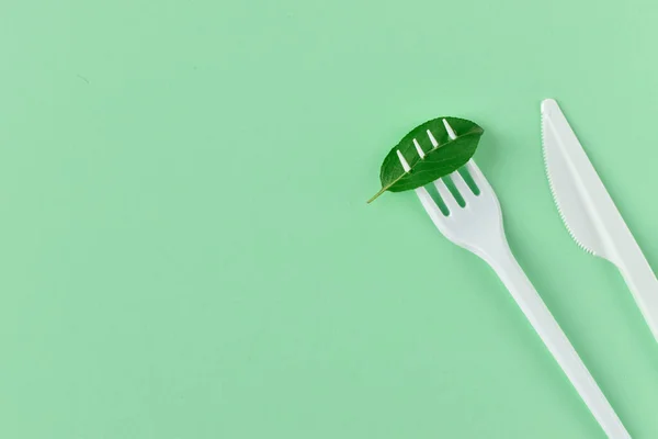 Garfo e faca feita de plástico em um fundo verde . — Fotografia de Stock