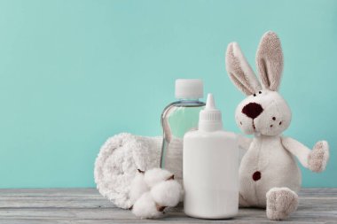 Yağlı bir kap, bir şişe şampuan, bebek pudrası ve ahşap bir rafta oyuncak tavşan. Rahatlayın. Metin, tırnak içinde, özdeyişler ya da nane arkaplanındaki logo için boş yer.