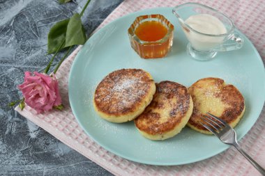 Ekşi krema ve reçelin yanında bir tabakta üç cheesecake var. Sağlıklı beslenme.