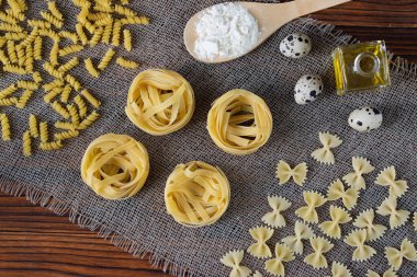 İçinde un, tereyağı, yumurta gibi malzemeler olan çeşitli kuru makarnalar. çeşitli makarna, makarna, fusilli, conciglio, rigatoni, farfalle, penne çeşitleri. Akşam yemeği. Sağlıklı yiyecekler. Flalay. Üst görünüm.