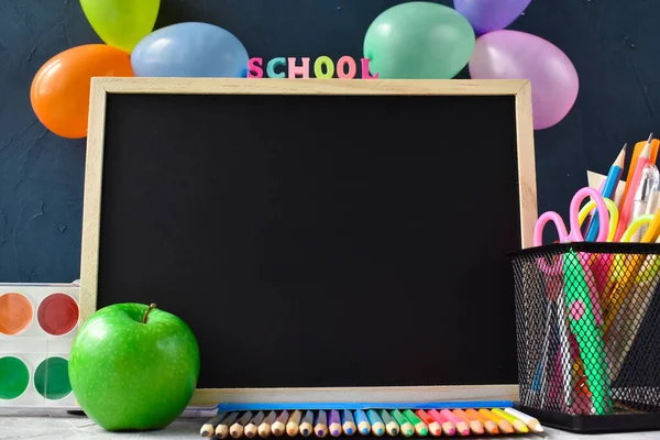Je retourne à l'école. Une commission scolaire avec une pomme verte et de la papeterie sur fond bleu avec des ballons. Espace de copie. — Photo